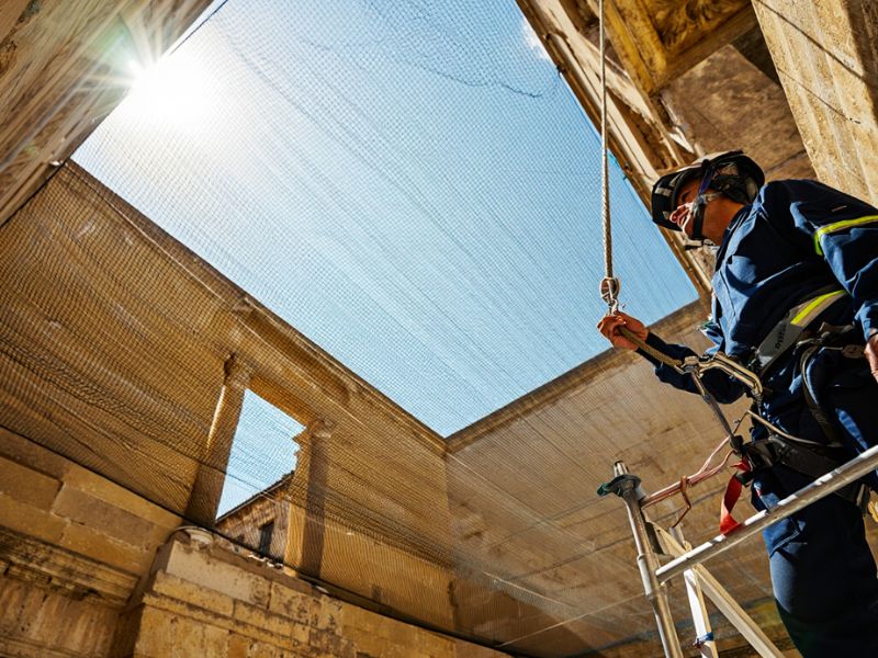 Installazione tecnica di dissuasori antipiccione a spillo in acciaio inox su cornicione in travertino a Roma